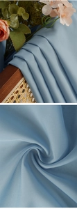 Macro shot showing light blue sheer curtain fabric with subtle satin sheen and fine texture