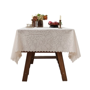Beige floral lace tablecloth with scalloped edges and retro crochet patterns on a table