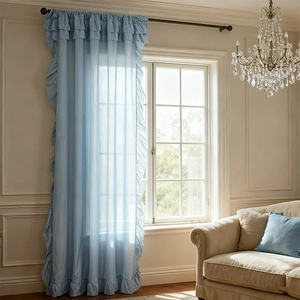 Light blue ruffled sheer curtains with elegant french ruffles hanging on black metal rod