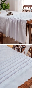 Close-up of white jacquard tablecloth featuring vintage damascus floral and scalloped edges