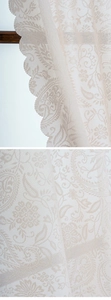 Detailaufnahme von cremefarbenem Spitzengewebe mit Paisley-Blumenmustern und Wellenkante