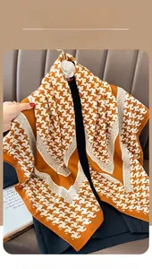 Detail of houndstooth silk scarf in orange and white with a smooth glossy texture