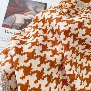 Detail of caramel houndstooth knitted scarf texture resting on a vintage magazine