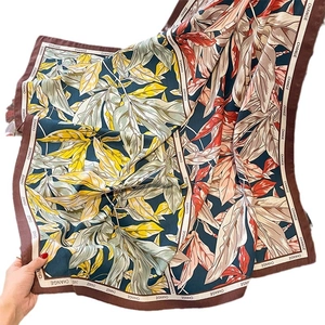 Satin silk scarf with navy botanical leaf pattern and brown 'CHANGE' printed border