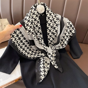 Close-up of classic black and white houndstooth scarf on a black turtleneck dress