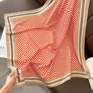 Close-up of striped orange and white silk shawl displayed on a leather sofa with accessories