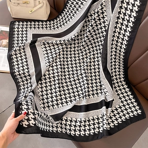 Close-up of elegant black and white houndstooth silk scarf on premium leather background