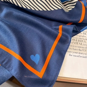 Nahaufnahme der marineblauen Fischgräten-Schal mit orangefarbenem Saum und Herz
