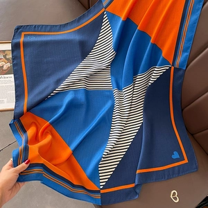 Detail eines quadratischen Seidenschals mit blau-orangen Geometrie- und Streifenmustern