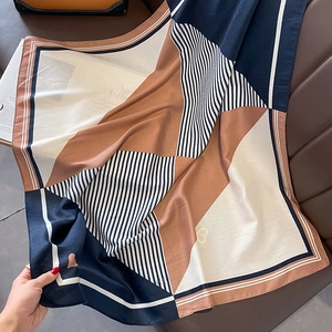 Detailaufnahme von Seidenschal mit geometrischem Patchwork und Streifen auf Leder