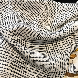 Macro shot showing the thick black and white houndstooth wool-feel fabric texture
