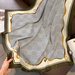 Close-up of houndstooth plaid scarf texture with olive green borders and yellow accents