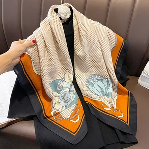 Vintage houndstooth scarf with orange borders and blue rose pattern draped on a leather seat
