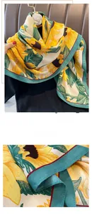 Detail of the elegant sunflower print scarf with turquoise borders and red stitched edges