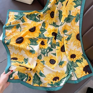 Detail of sunflower print silk scarf with green borders on leather seat texture