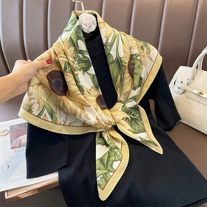 Elegant sunflower print silk scarf tied as a necktie on a black shirt with a luxury bag