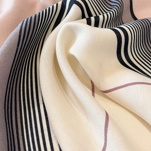 Close-up of herringbone weave fabric and geometric stripes on an elegant square scarf