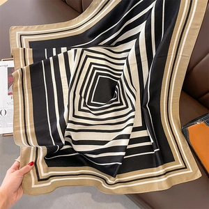 Detail of geometric pattern silk scarf with black, white, and tan stripes on leather