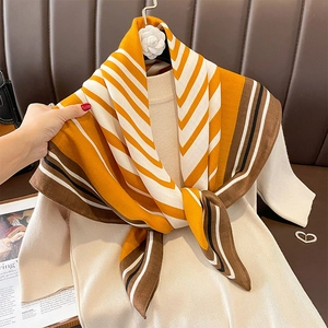 Striped winter scarf with yellow and brown patterns styled on a beige knit sweater
