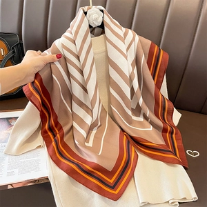 Striped square scarf shawl in beige and brown, elegantly draped on a leather surface