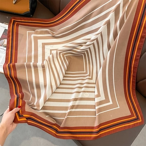 Detail of silk satin square scarf with geometric stripe pattern on brown leather background
