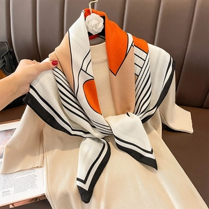 Striped geometric silk-feel scarf with vibrant orange and beige blocks on knit top