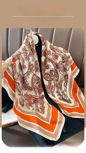 Close-up of vintage paisley pattern on a soft long scarf with vibrant orange and cream tones