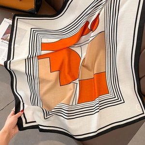 Detail of elegant striped scarf with orange color blocking on luxury leather backdrop