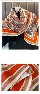 Close-up of orange paisley patterned silk scarf detailing fine stitching and edge quality