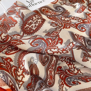 Macro detail of silk-like paisley scarf with soft draping and elegant orange patterns