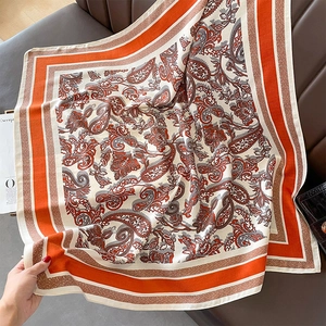 Close-up of vintage orange and cream paisley print scarf on a leather background