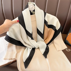 Eleganter Seidenschal mit geometrischem Farbmuster in Schwarz, Weiß und Camel über Pullover