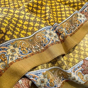 Close-up detail of vintage yellow silk scarf with paisley floral border and twill texture