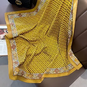 Close-up of vintage yellow silk scarf with chain and floral patterns on leather