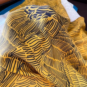 Close-up of mustard yellow scarf showing thick texture and modern abstract black lines