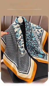 Detail eines Seidenschals mit Blumenmuster, blauen Motiven und orangefarbenem Rand