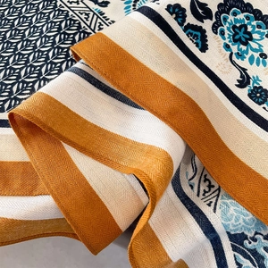Detailaufnahme von Retro-Blumenmuster und Fischgräten-Webstruktur auf einem weichen Schal