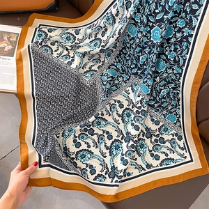 Detail eines bedruckten Schals mit Paisleymuster und senfgelbem Rand auf Lederhintergrund