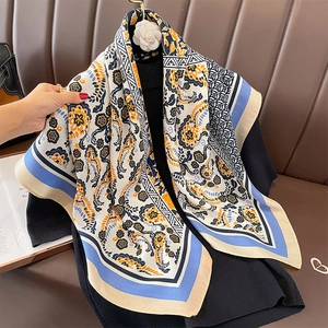 Eleganter Seidenschal mit Paisleymuster in Creme und Orange auf einem Ledersofa