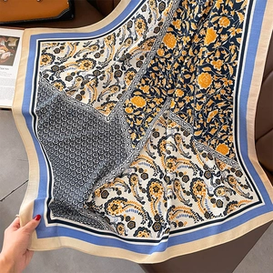 Makro-Detail eines Seidenschals mit Paisley-Blumendruck auf Lederhintergrund