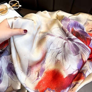 Close-up of printed silk scarf showing luxurious texture and vibrant floral patterns