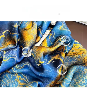 Detail eines blau-goldenen Marmor-Seidenschals mit weicher Satin-Textur und elegantem Fall