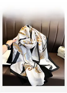 Detail of elegant paisley floral scarf with golden pattern and black border on white silk