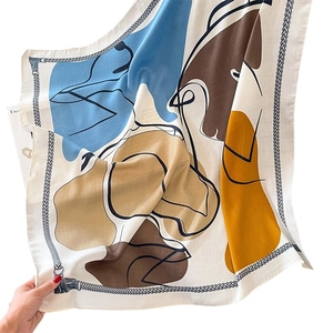 Abstract geometric silk scarf with blue and yellow patterns in a dynamic hand-held pose