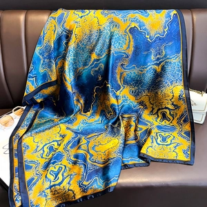 Seidenschal mit blau-gelbem Marmormuster auf Ledersofa mit eleganten Modeaccessoires