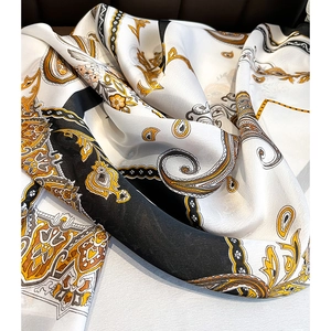 Elegant paisley print silk scarf in black, white, and gold with a satin finish