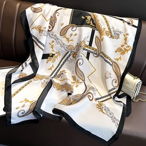 Elegant black and gold paisley silk scarf displayed on a luxury leather sofa