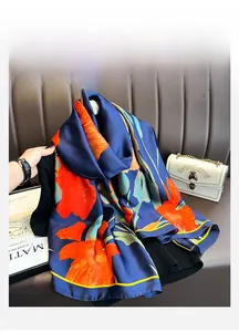 Détail d'un foulard en soie bleu marine avec motif floral orange sur un canapé en cuir