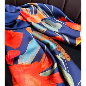 Gros plan détaillé d'une écharpe en soie aux motifs floraux abstraits bleu et orange