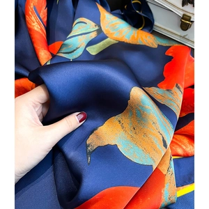 Gros plan d'un foulard en soie imprimé montrant la texture satinée et les motifs floraux